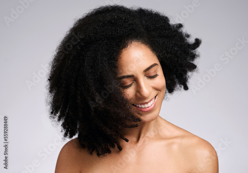 Happy, natural and hair care shake of black woman satisfied with cosmetic treatment texture and volume. Self love, smile and happiness of african hair and skincare girl in gray studio background.