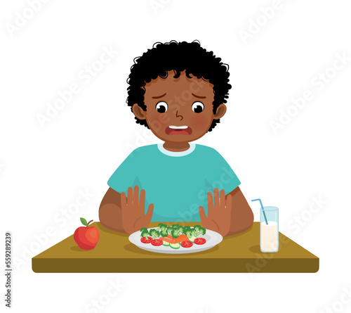 Cute little African boy picky eater refusing to eat vegetables