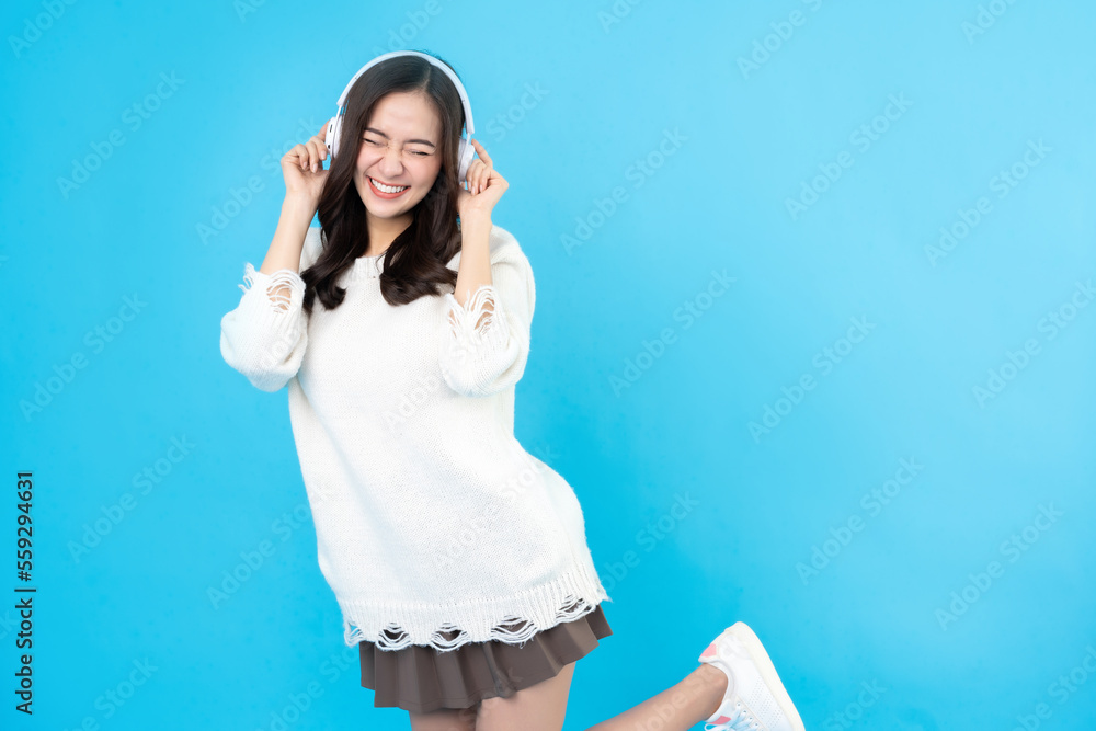 Beautiful Asian woman with long hair, casual wear, wearing white wireless headphones. Very happy and emotional to listen to music. sent through bright faces on the blue background in the studio. Beautiful Asian woman with long hair, casual wear, wearing white wireless headphones. Very happy and emotional to listen to music. sent through bright faces on the blue background in the studio.