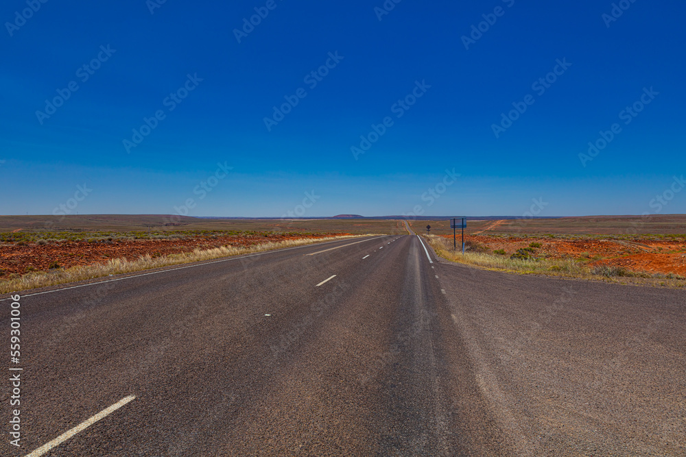 On the road side of the Stuart highway. Along the deserted barren vast landscape of the Australian outback. The grey red asphalt cuts through the desert of central Australia. Deserted steppe