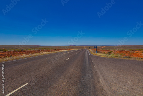 On the road side of the Stuart highway. Along the deserted barren vast landscape of the Australian outback. The grey red asphalt cuts through the desert of central Australia. Deserted steppe photo
