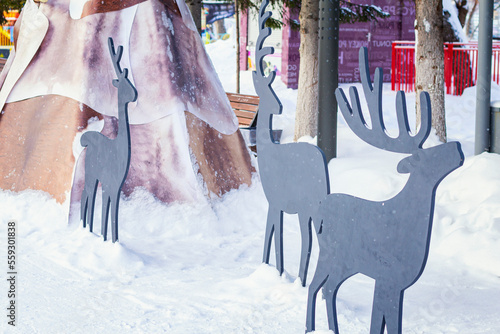 Sculpture of deers and wigwam as winter decoration of park. City recreation park adorn photo