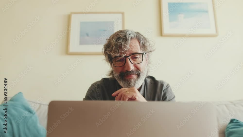 Close up, elderly man working on laptop sitting on the sofa in the living room. Close up, elderly man working on laptop sitting on the sofa in the living room.