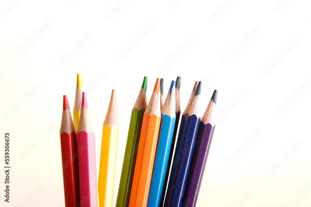 colored pencils against the background of a desk, notebook, white wall colored pencils against the background of a desk, notebook, white wall