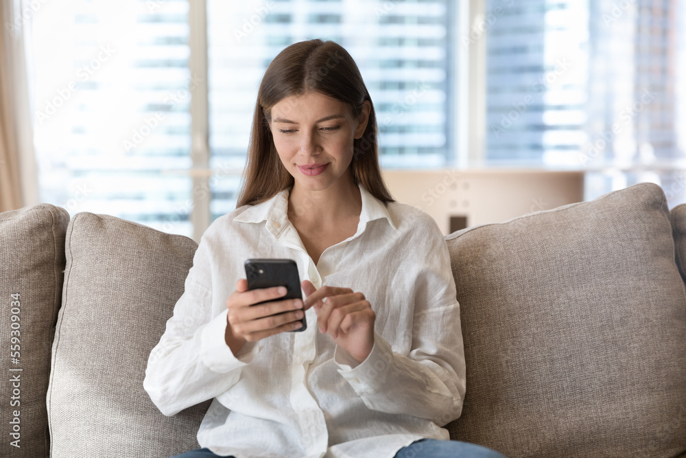 Young 25s pretty woman using smartphone resting on sofa at home, chatting in social media, search information, make order, spend free time on internet. Modern tech for fun, leisure and communication Young 25s pretty woman using smartphone resting on sofa at home, chatting in social media, search information, make order, spend free time on internet. Modern tech for fun, leisure and communication