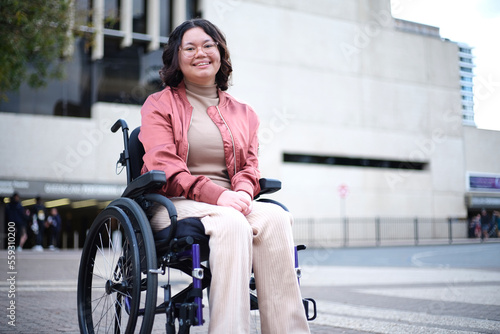 Smiling woman in pink with a disability sitting in a wheelchair outside photo