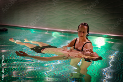 Therapeutic exercise in the pool. Woman receiving an aquatic therapy in the pool. Water relaxation and deep meditation. © jozefklopacka