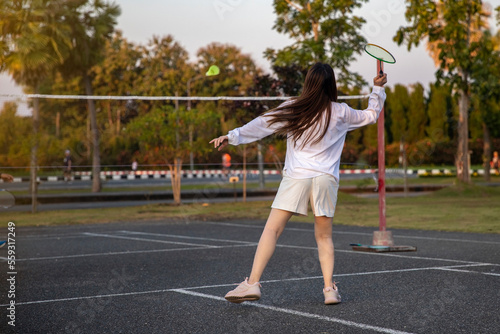 woman playing badminton in the park. urban asian sporty female having fun outdoor sports and game activity concept
