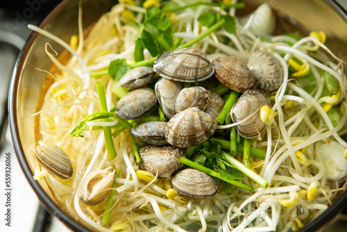 Clear clam soup boiling with vegetables in a pot 