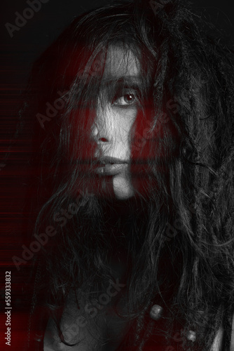 Beautiful woman studio portrait in red color split effect. Model with dreadlocks covering her face with messy hair. Woman with make-up looking at camera. Futuristic looking style © Rytis