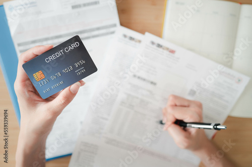 Top view left hand of asian woman holding credit card and calculate bills at home, plan money cost for saving, finance concept.