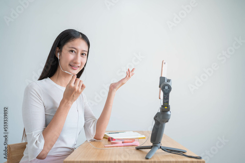 Young attractive asian woman blogger or vlogger talking on video call shooting with mobile phone and broadcast with internet subscribers. Social media influence people and Social communication.