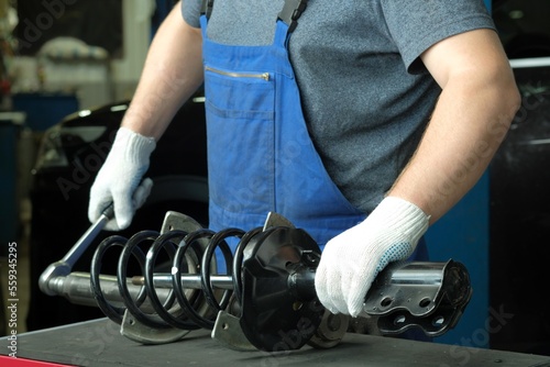 Repair and maintenance of the car at the dealership. An auto mechanic replaces the spring and shock absorber strut of the front suspension of the car. photo