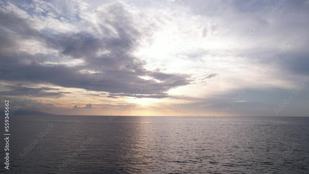 Feel breath of fresh air, camera fly low over calm sea, straight towards sunset. Dark and light clouds on the sky, setting sun hide behind them. Rippled water surface flashes below, empty sea around Feel breath of fresh air, camera fly low over calm sea, straight towards sunset. Dark and light clouds on the sky, setting sun hide behind them. Rippled water surface flashes below, empty sea around