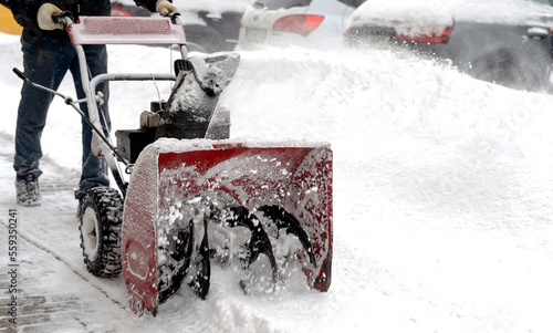 snowblower removes snow, a man cleans the yard outside © I