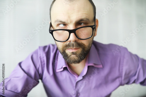 Fototapeta Naklejka Na Ścianę i Meble -  A cross-eyed bearded man is looking into the frame. Eye disease. The concept of an inexperienced specialist. Spy neighbor.