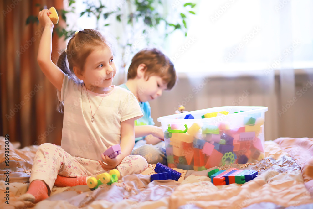 Children play construction set sitting on the sofa and watch cartoons on TV. Children play construction set sitting on the sofa and watch cartoons on TV.