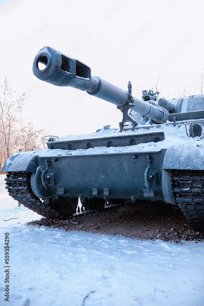 Tank under the snow in the forest. Winter tank camouflage. Battle tank in the snow on the roadside of highway. War in Ukraine in winter. Tank under the snow in the forest. Winter tank camouflage. Battle tank in the snow on the roadside of highway. War in Ukraine in winter.