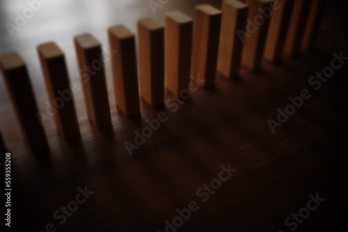 domino effect concept with wooden tiles blocked by hourglass with background