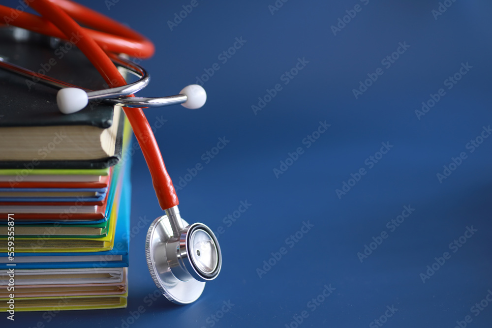 stethoscope on stack of medical guide book for doctor learning treatment at hospital. - obrazy, fototapety, plakaty 