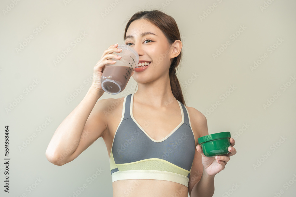 Diet meal replacement for weight loss, happy asian young woman, girl in sportswear, hand in holding protein shake bottle for drink supplement for muscle after workout at home. Healthy body care person Diet meal replacement for weight loss, happy asian young woman, girl in sportswear, hand in holding protein shake bottle for drink supplement for muscle after workout at home. Healthy body care person