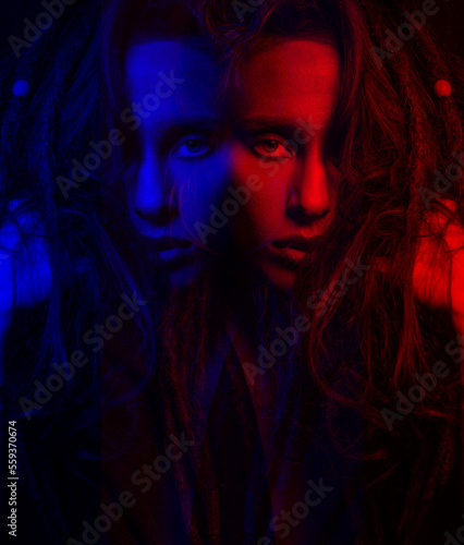 Fashion concept. Beautiful woman studio portrait in red and blue color illuminated effect. Model with dreadlocks looking at camera with seductive look. Futuristic looking style