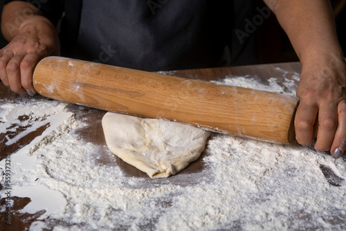 Chef is rolling the dough with the rolling pin on the on the table. Hands close-up.Cooking pasta, bread, spaghetti, khachapuri, food concept