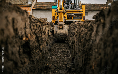 Cropped picture of a backhoe digging soil and making foundation at construction site.