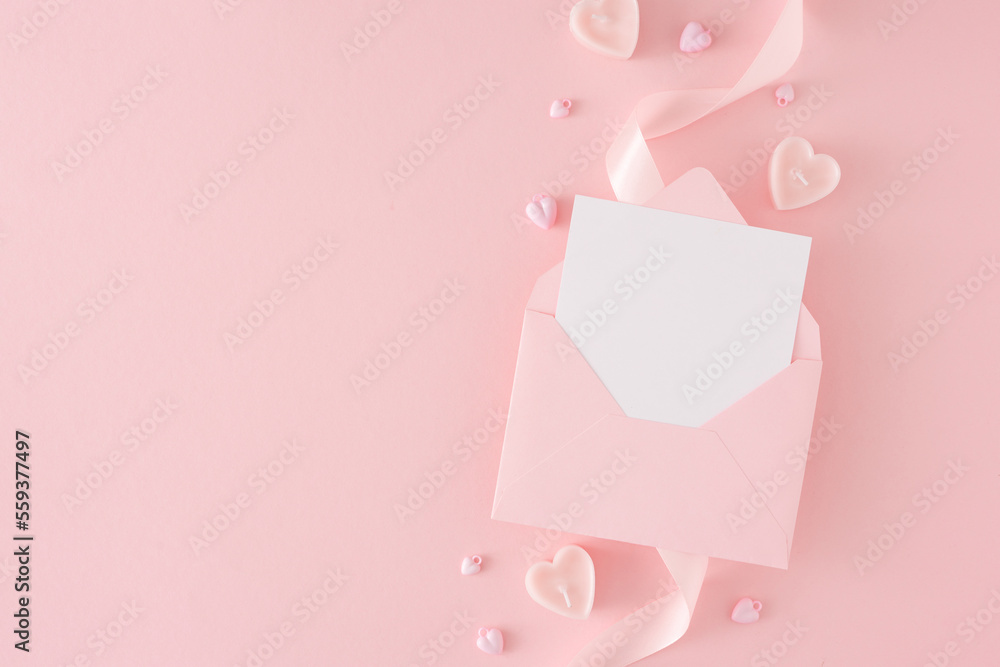 Women day concept. Flat lay photo of envelope with letter, silk ribbon and heart shaped candles on pastel pink background with copy space. Mother's day Or Valentines idea.