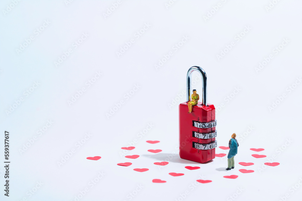 Obraz premium a young woman sits on a red padlock and looks down at her partner, white background with red hearts. Valentine's day holiday concept