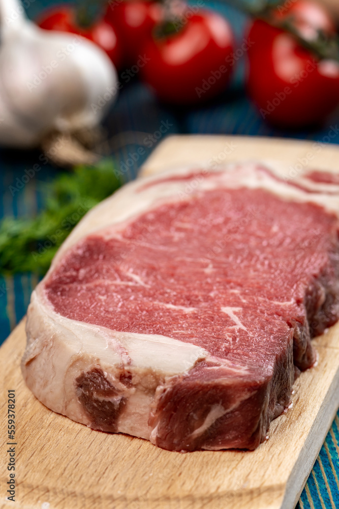 raw beef steak with vegetables and spices on wooden table