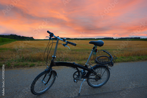Fototapeta Naklejka Na Ścianę i Meble -  bike tour with folding bike along the fields at sunset