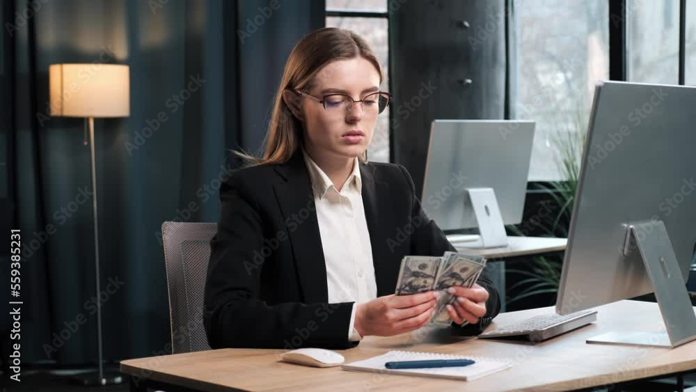 Serious girl counting money cash in modern loft office. Successful businesswoman getting bundle of money indoor. Businesswoman counts money profit, calculates dividends cash money profits finances. Serious girl counting money cash in modern loft office. Successful businesswoman getting bundle of money indoor. Businesswoman counts money profit, calculates dividends cash money profits finances.