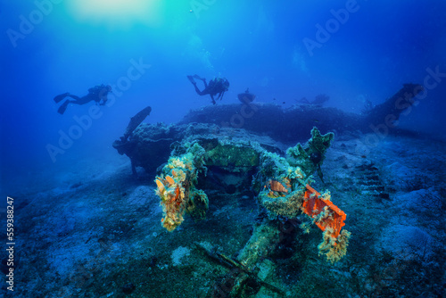 A scuba diver explores a sunken world war two fighter propeller airplane at the seabed of the Aegean Sea, Naxos island, Greece