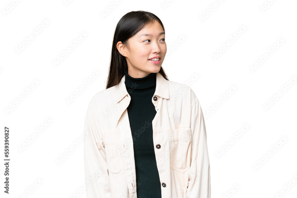 Young Asian woman over isolated chroma key background looking to the side and smiling