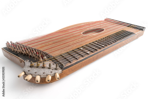 High angle closeup horizontal studio shot of vintage, old wooden zither isolated on white background. Detail of zither mechanics and tuning pins. Dusty and scratched instrument. photo