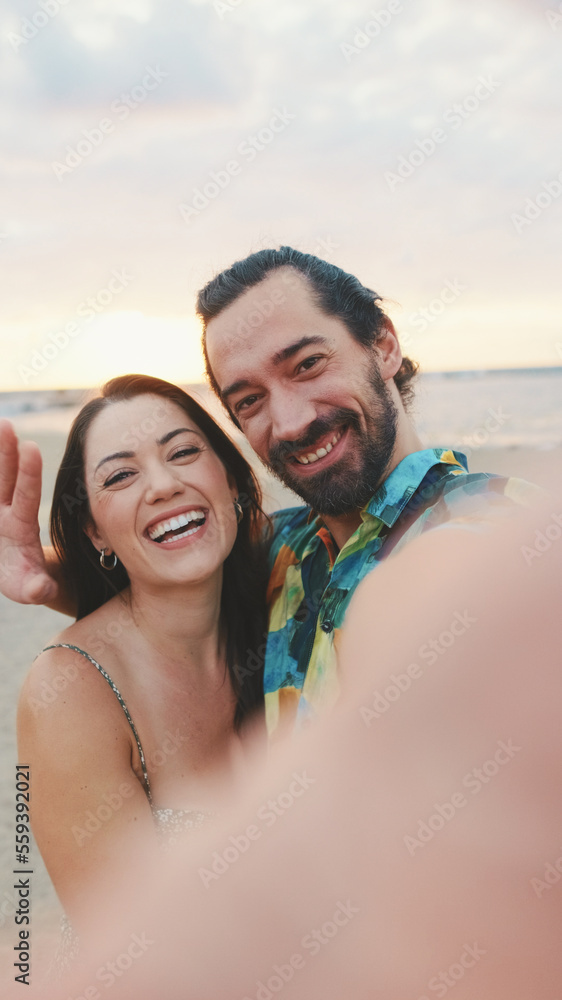 Laughing couple making video call while standing on the beach Laughing couple making video call while standing on the beach