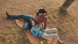 Close-up of young couple lying on blanket in the park from outside. Top view