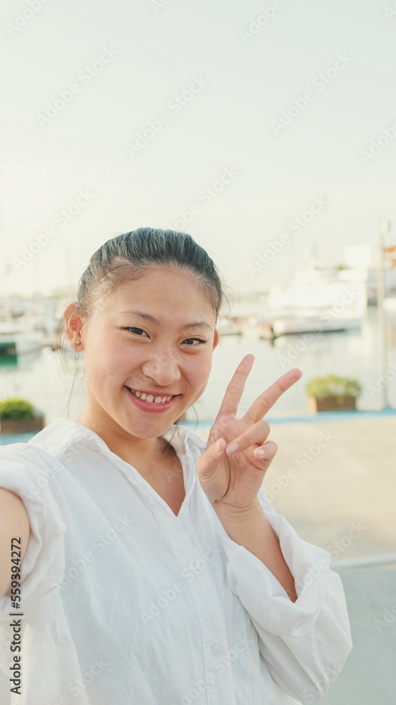 Young woman taking selfie on mobile phone on seascape background