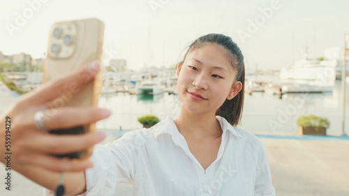 Young woman taking selfie on mobile phone on seascape background