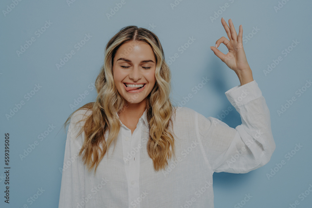 Crazy blonde woman making ok gesture while showing tongue Crazy blonde woman making ok gesture while showing tongue
