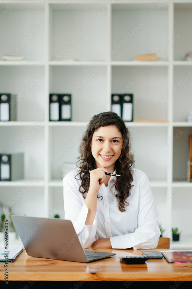 Attractive female office worker business suits smiling at camera in office Attractive female office worker business suits smiling at camera in office
