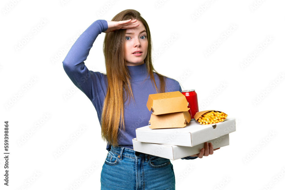 Young pretty woman holding pizzas and burgers over isolated chroma key background doing surprise gesture while looking to the side Young pretty woman holding pizzas and burgers over isolated chroma key background doing surprise gesture while looking to the side