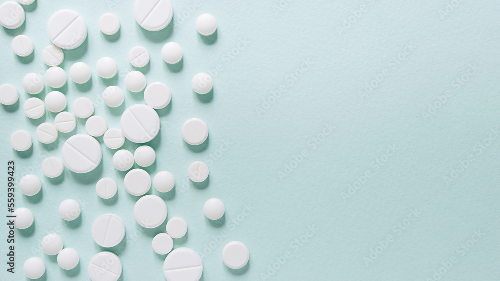 Scattered white pills on blue table. Mock up for special offers as advertising, web background or other ideas. Medical, pharmacy and healthcare concept. Copy space. Empty place for text or logo Scattered white pills on blue table. Mock up for special offers as advertising, web background or other ideas. Medical, pharmacy and healthcare concept. Copy space. Empty place for text or logo