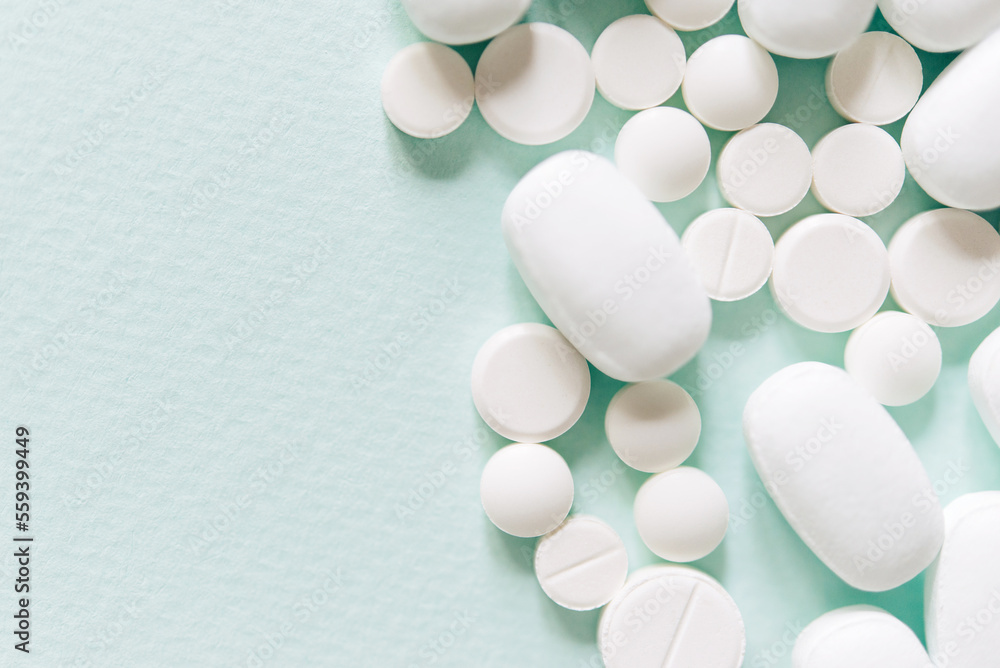 Scattered white pills on blue table. Mock up for special offers as advertising, web background or other ideas. Medical, pharmacy and healthcare concept. Copy space. Empty place for text or logo Scattered white pills on blue table. Mock up for special offers as advertising, web background or other ideas. Medical, pharmacy and healthcare concept. Copy space. Empty place for text or logo