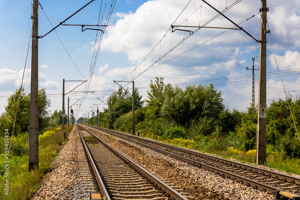 Tracks of an electric railway line on a hot summer day. Perspective shot from human eye level.