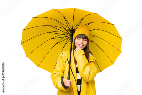 Little girl with rainproof coat and umbrella over isolated chroma key background looking to the side and smiling