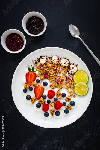 Yogurt with strawberries, blueberries, raspberries and muesli in bowl on wooden table 