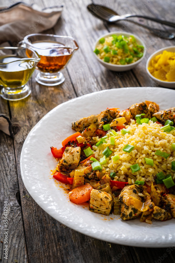 Fried chicken nuggets, bulgur groats, carrots and red pepper on wooden background
Fried chicken nuggets, bulgur groats, carrots and red pepper on wooden background