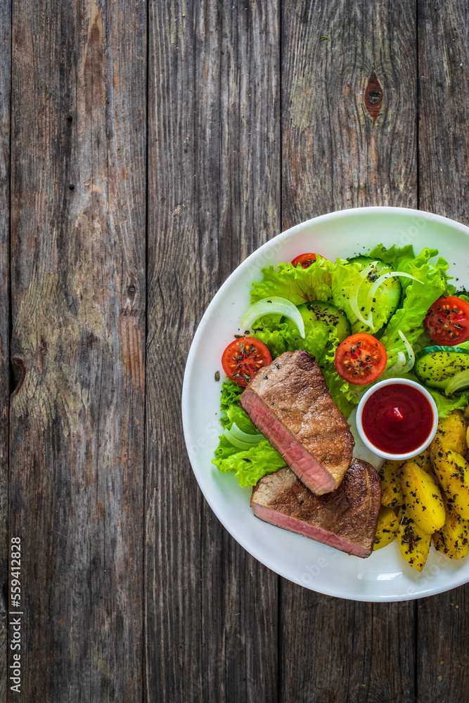 Fried beef sirloin with potatoes and vegetables on wooden table
Fried beef sirloin with potatoes and vegetables on wooden table